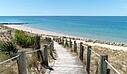 [Translate to Espagnol:]  A scenic wooden boardwalk with rope railings cutting through sand dunes, near a luxury Les Castels campsite